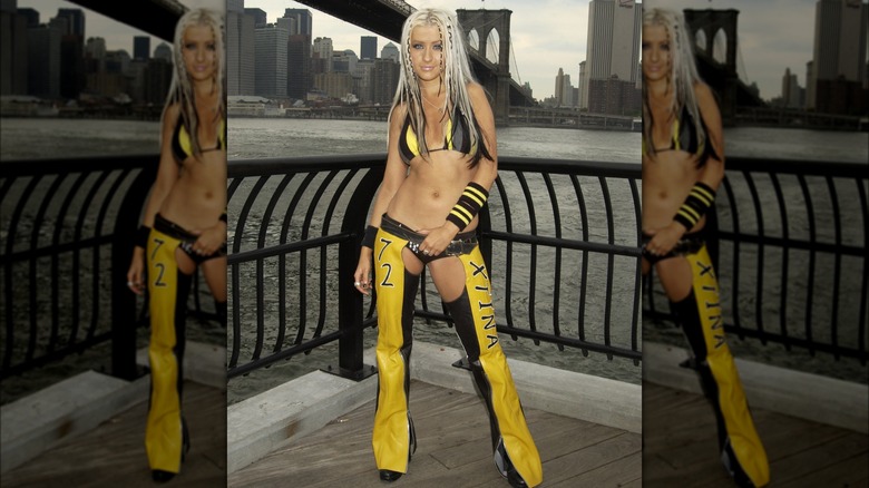 Christina Aguilera wearing a yellow and black striped bikini top, matching wristband, and black and white long braids in her hair