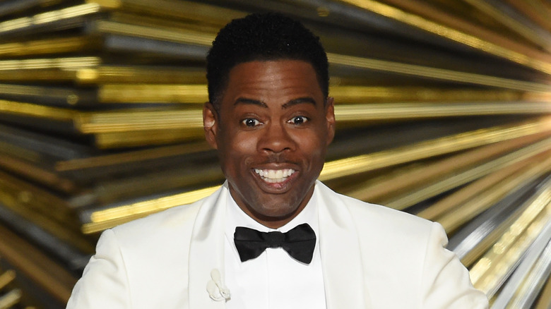 Chris Rock smirking in white jacket