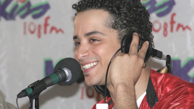 Mario Vasquez in front of a microphone, holding headphones to his ears