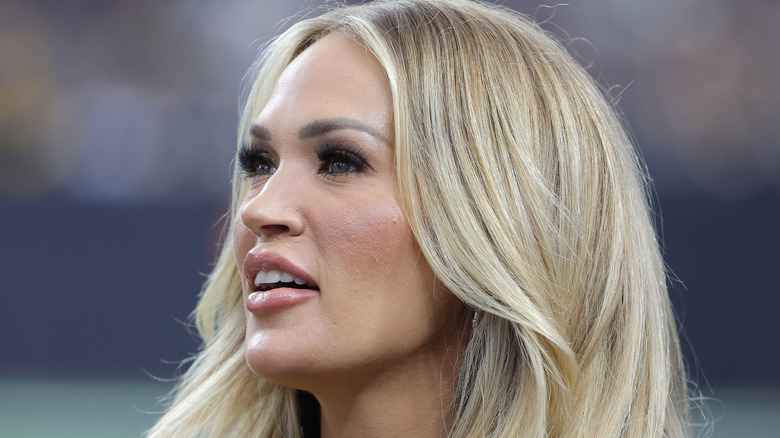 Carrie Underwood at a football game lookig up with her mouth open