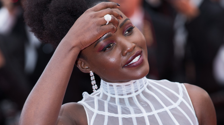 Lupita Nyong'o places her hand on her head