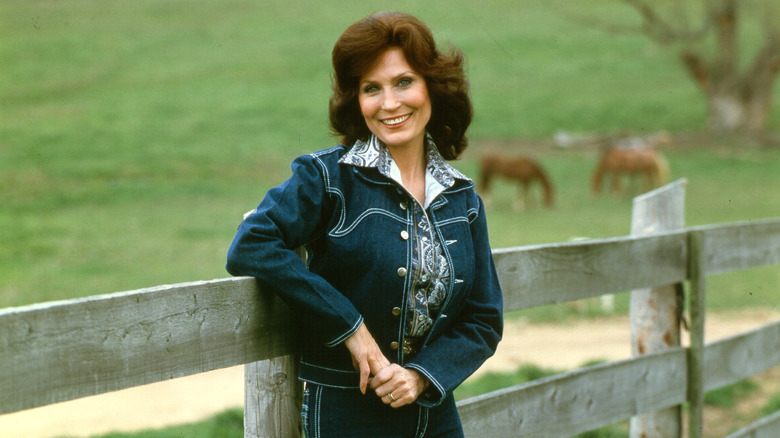 Loretta Lynn leaning against fence