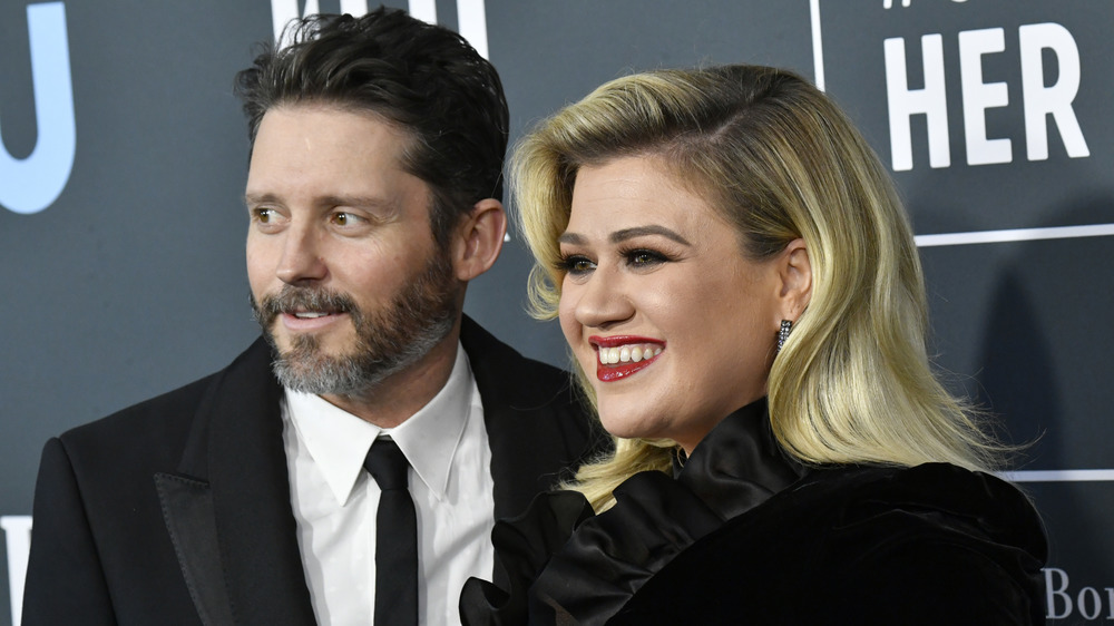 Brandon Blackstock and Kelly Clarkson smiling while looking off to the side