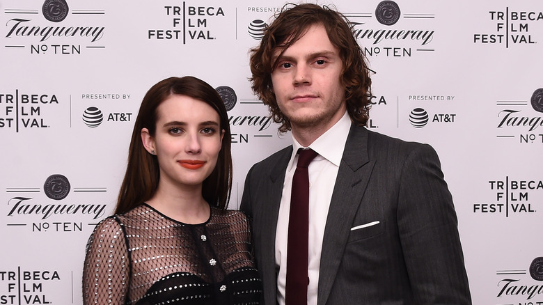 Emma Roberts and Evan Peters smiling closed mouthed looking at the camera