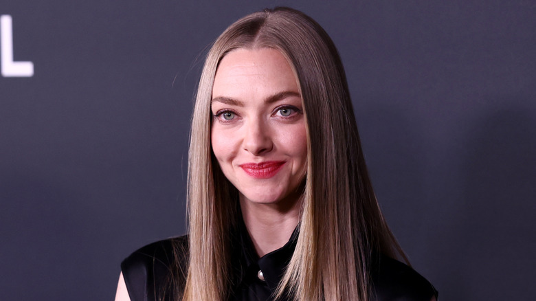 Amanda Seyfried wearing a black collared blouse with long straight silver blonde hair