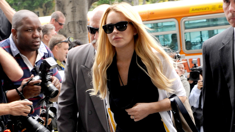 Lindsay Lohan wearing a black jumpsuit and white sweater while walking into court