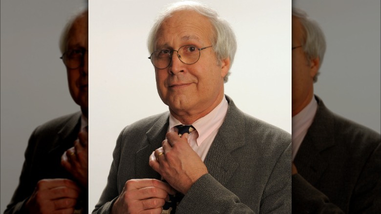 Chevy Chase adjusting tie and posing