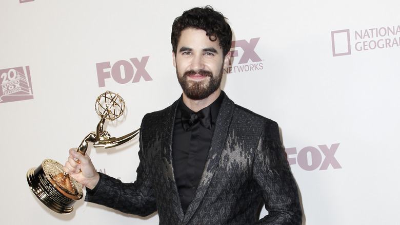 Darren Criss smiling, holding Emmy Award 