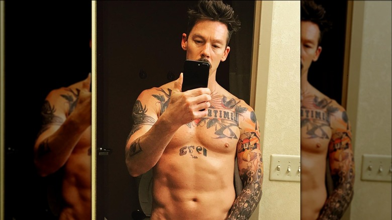 Shirtless David Bromstad looking at phone