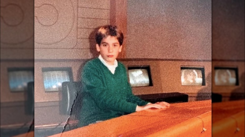 Teenage David Muir sitting behind an anchor desk