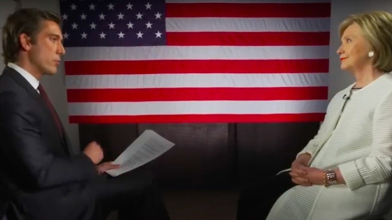 David Muir interviewing Hillary Clinton in front of an American flag