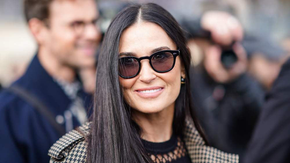 Demi Moore wears tan sun glasses smiles at the camera at an event