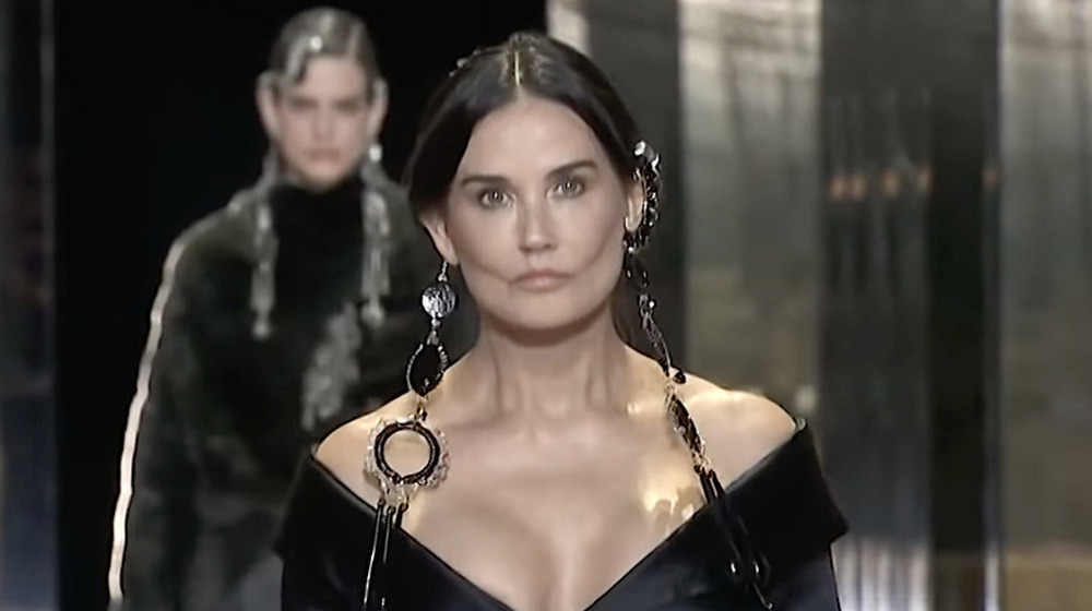 Demi Moore wearing black dangly earrings walks in a Fendi show