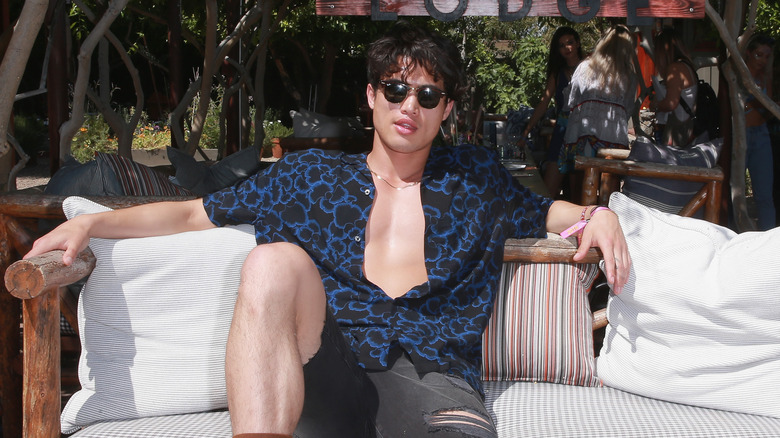 Charles Melton sprawled on an outdoor couch