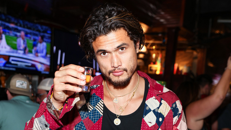 Charles Melton holding a drink at a bar