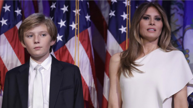 Barron and Melania Trump stand in front of American flags