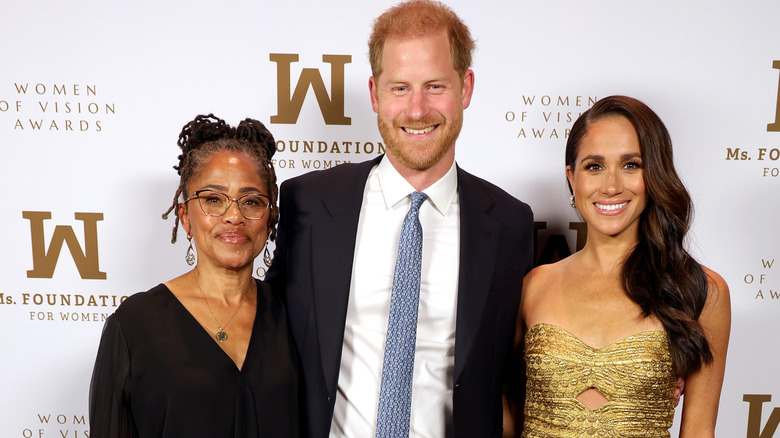 Doria Ragland, Prince Harry, and Meghan Markle posing on the red carpet