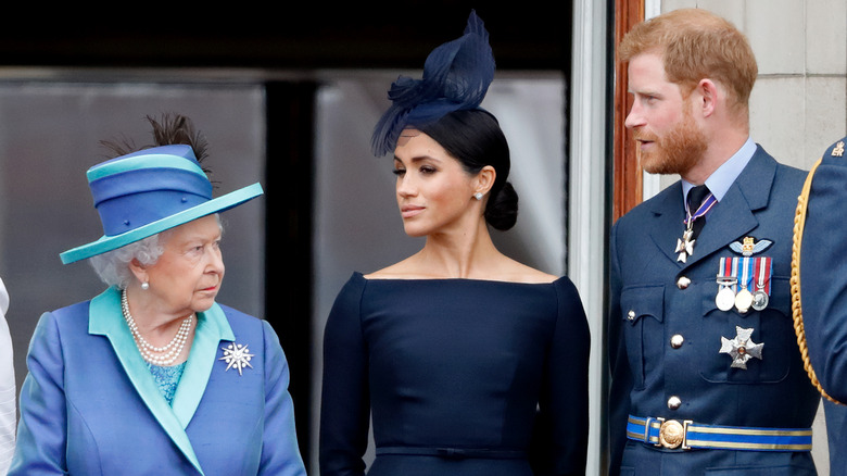 queen elizabeth ii, meghan markle, and prince harry standing side by side