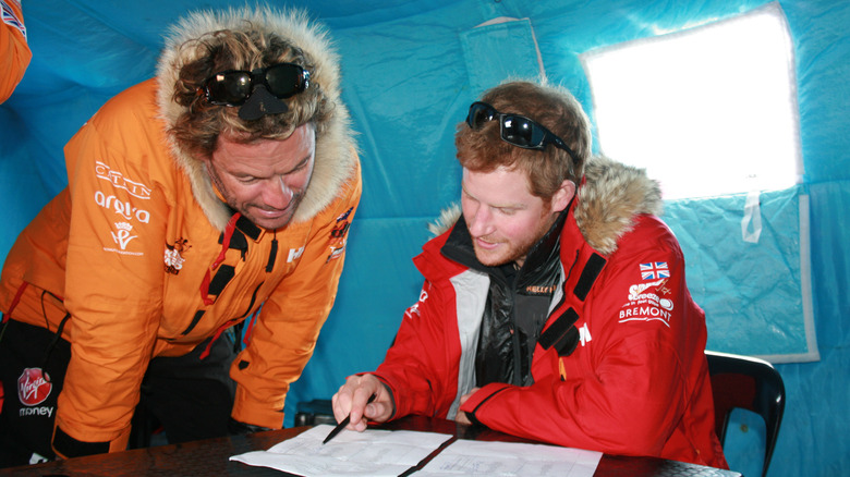 Dominic West and Prince Harry looking at a paper