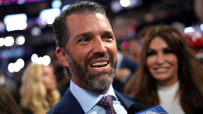 Donald Trump Jr. speaking to the media at the RNC with Kimberly Guilfoyle behind him