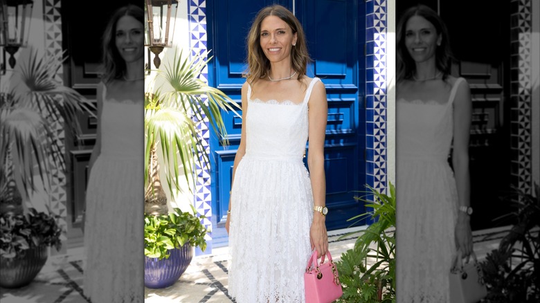 Bettina Anderson in a white dress holding a pink purse