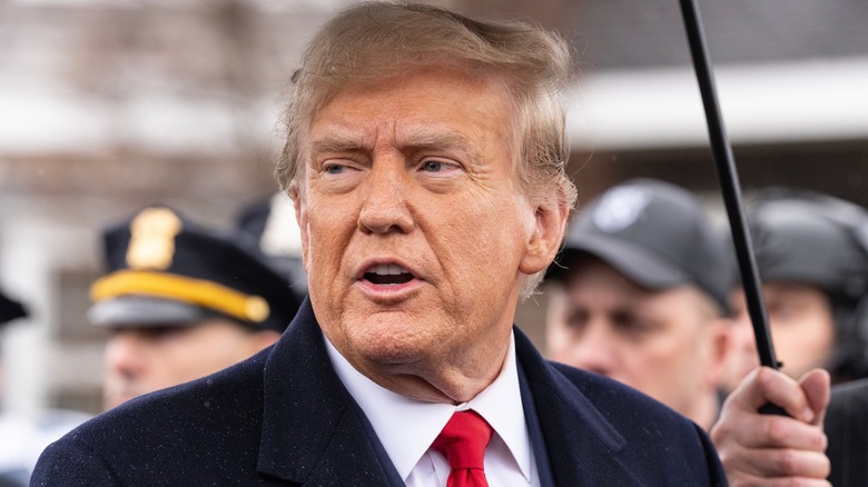 Donald Trump standing under umbrella