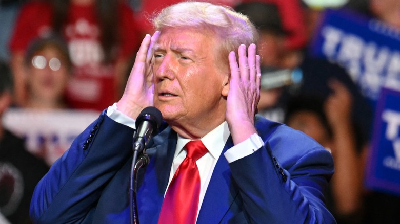 Donald Trump with his hands on his ears