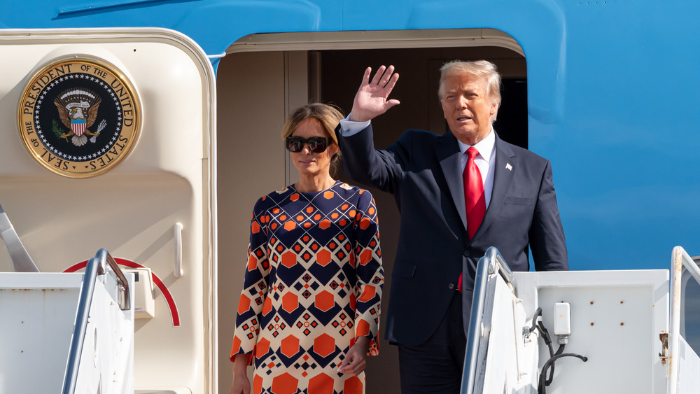 Melania and Donald Trump waving in front of the doorway to Air Force One