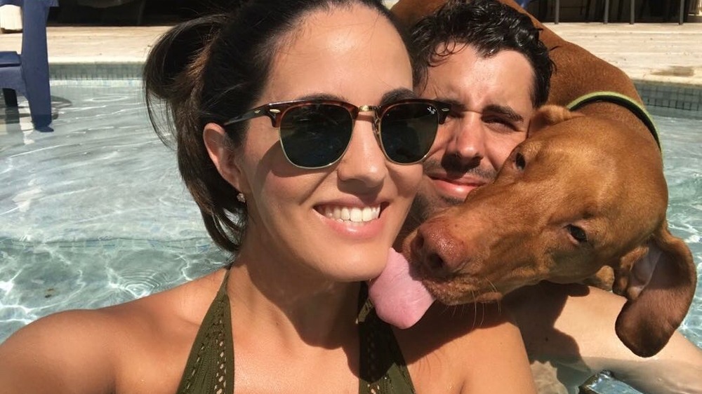 Dr. Jackie Duenas and her husband with a dog in the pool 