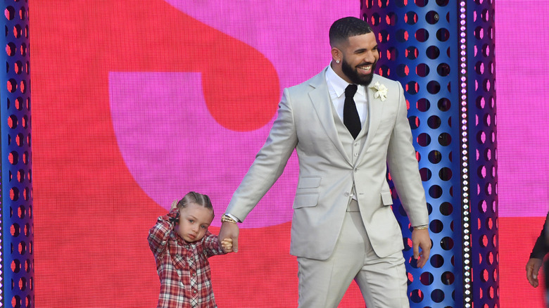 Drake smiling while holding his son