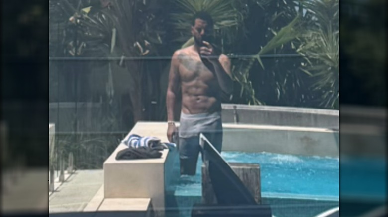 Drake taking a shirtless selfie in a window