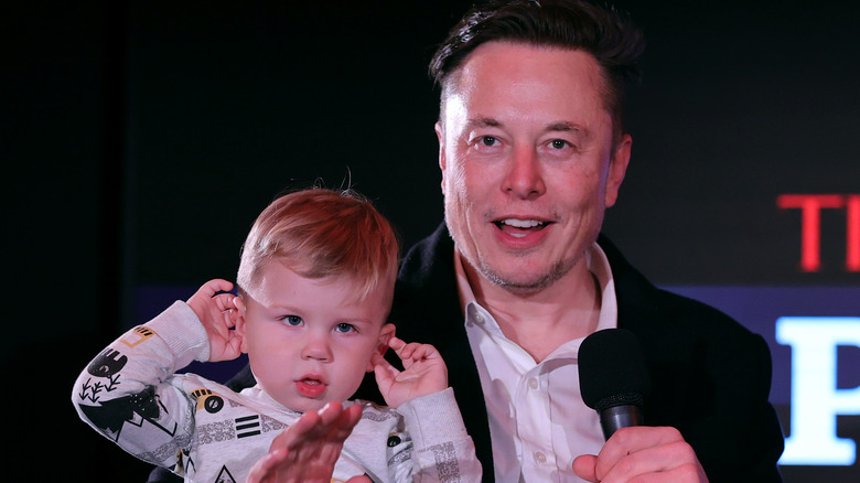 Elon Musk waving holding son in his arm