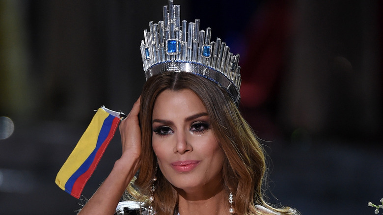 Miss Colombia wearing silver crown holding flag