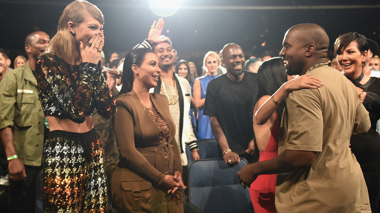 Taylor Swift and Kim Kardashian smiling at Kanye West