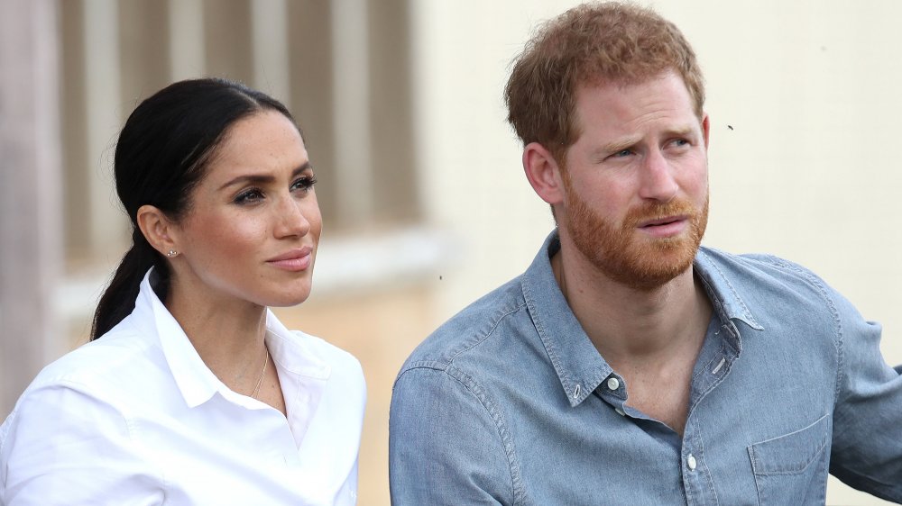 Meghan Markle, Prince Harry both dressed in button-down shirts, looking serious