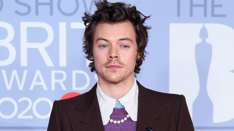 Harry Styles wearing a pearl necklace and jacket