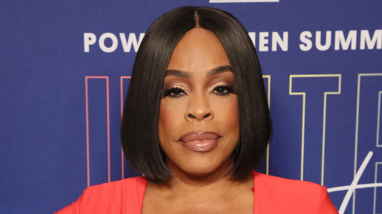 Niecy Nash poses in salmon-colored suit