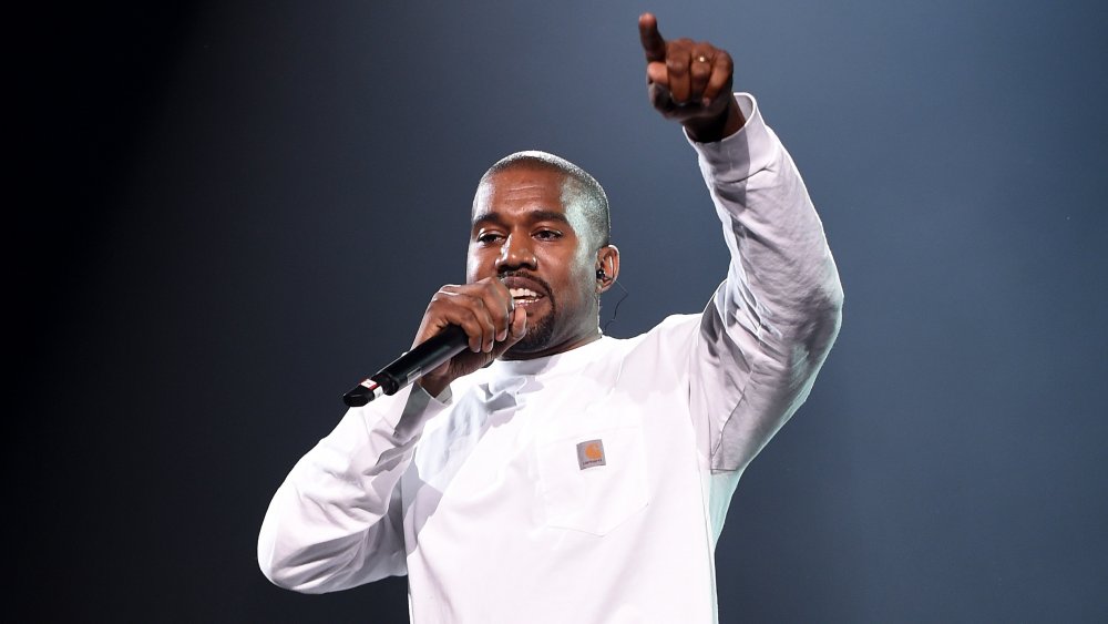 Kanye West in a white, long-sleeved shirt, performing during a concert