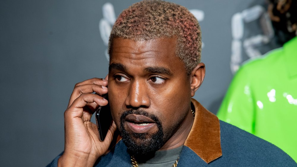 Kanye West in a blue-and-brown blazer, talking on the phone