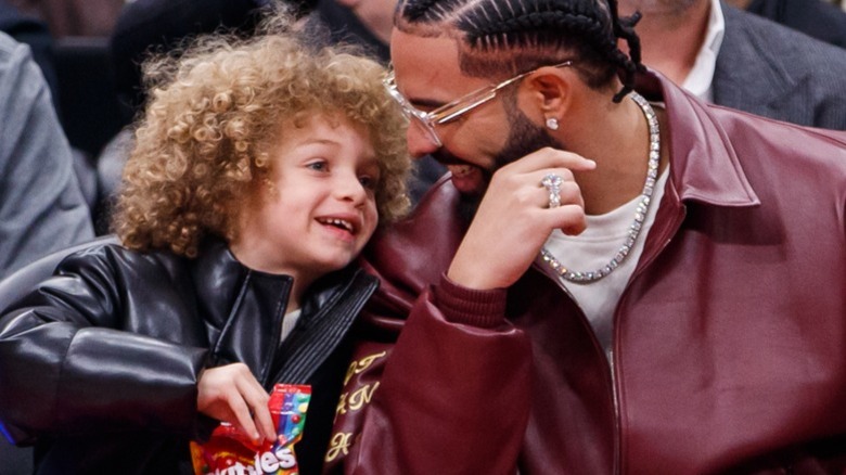 Drake and Adonis whispering at a basketball game