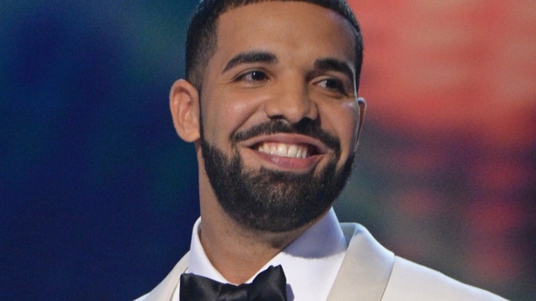 Drake smiles and looks left onstage