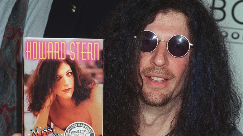 Howard Stern holding up book