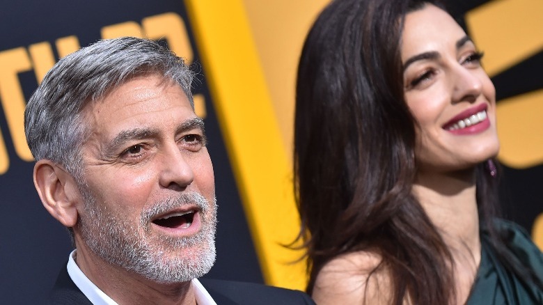 George Clooney talking and Amal Clooney smiling 