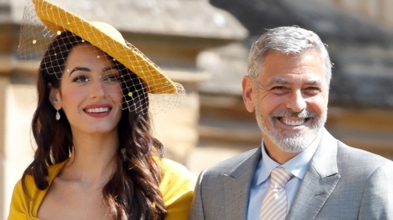 Amal Clooney in yellow hat and George Clooney smiling 