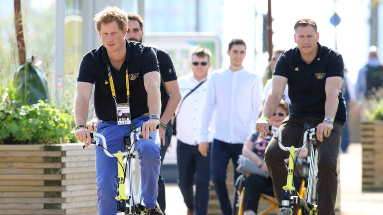 Prince Harry riding bike with his Police Protection Officer in 2014