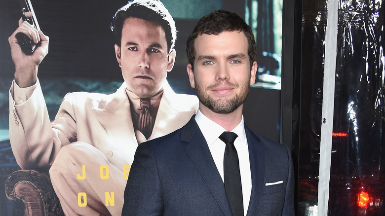 Austin Swift posing in front of a poster with Ben Affleck on it