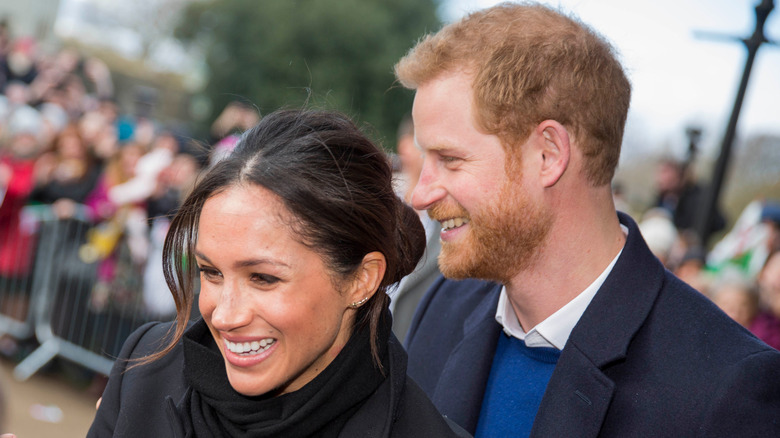 Harry and Meghan smiling outside at public event