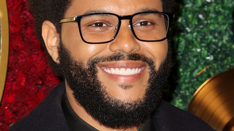 The Weeknd with wide smile and glasses