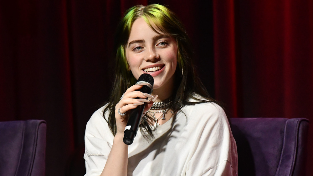 Billie Eilish smiling and holding a microphone 