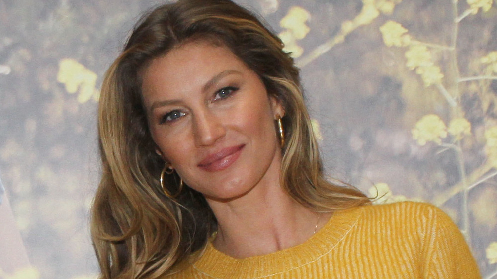 Gisele Bundchen posing against a leafy backdrop